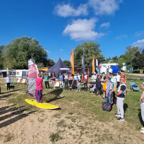 Groupe réuni sur la plage avant une session de windsurf