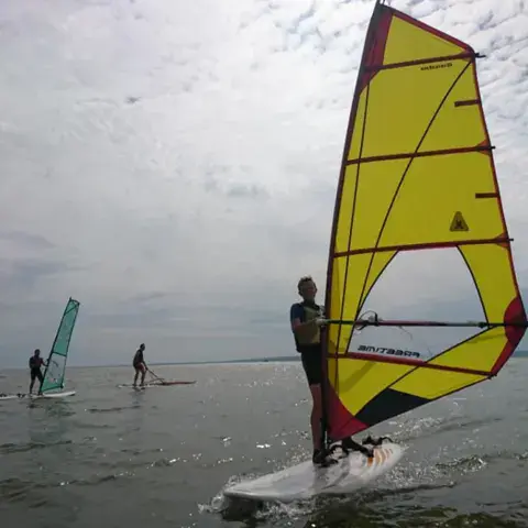 Véliplanchiste avec une voile jaune sur la lagune