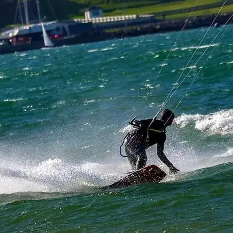 Deux kitesurfeurs sur l'herbe avec leur aile étalée, au soleil couchant