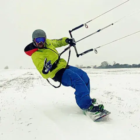 Snowkiteur à snowboard tracté par son aile
