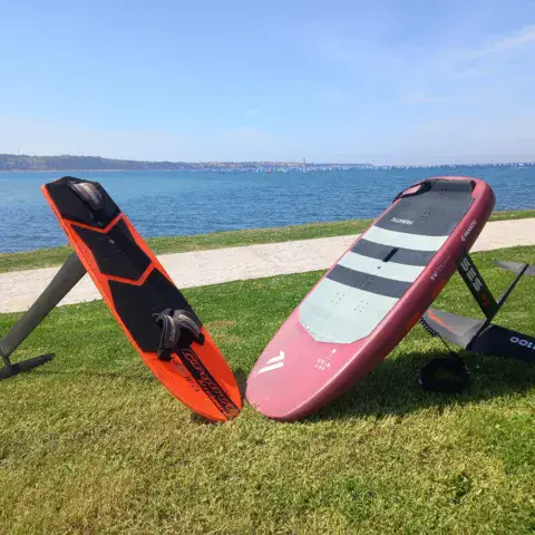 Deux planches à foil posées sur l'herbe, face à la mer