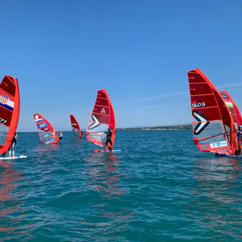 Planches à voile à foil sur une mer calme, avec la côte au loin