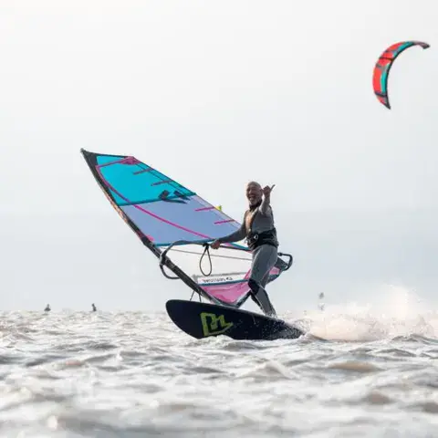 Un véliplanchiste à pleine vitesse sur le lac, devant les collines