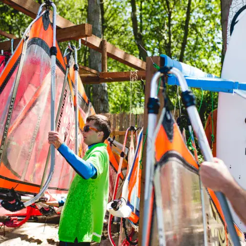 Moniteurs en polo vert préparant le matériel de windsurf