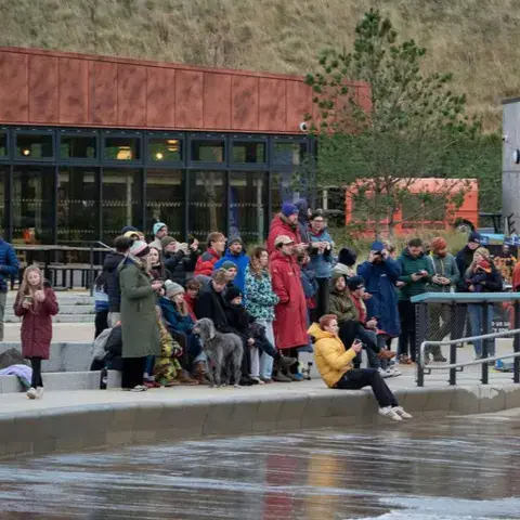 Public au bord du bassin à vagues devant le bâtiment