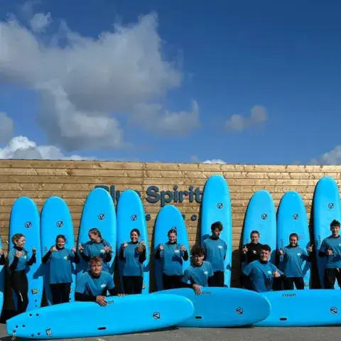 Équipe devant des planches de surf alignées