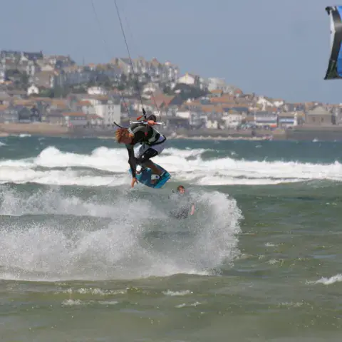 Saut de kitesurf devant une ville côtière