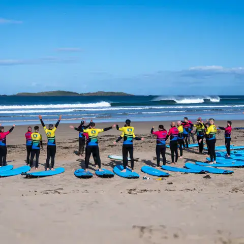 Groupe d'élèves avec leurs planches sur la plage