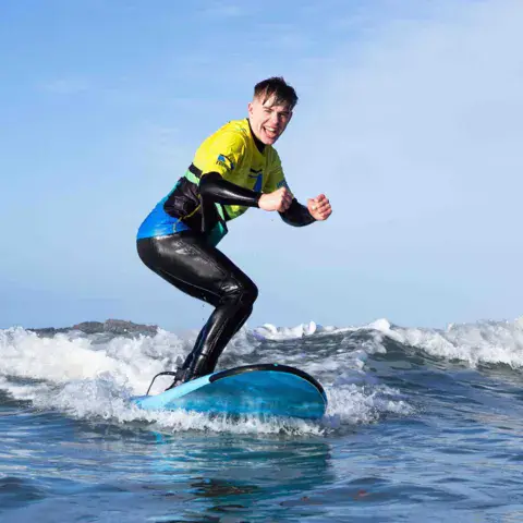Élève debout sur sa planche dans les vagues