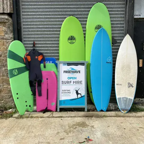 Planches de surf de location alignées devant un mur