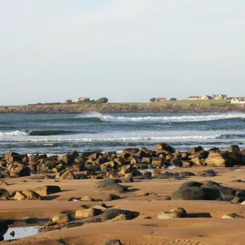 Plage de rochers et de sable avec des vagues au large