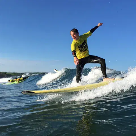 Surfeur en pleine vague avec une combinaison jaune
