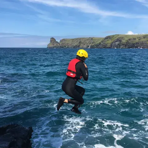Saut de falaise en combinaison et casque (coasteering)