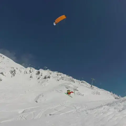 Kite orange au-dessus d'un versant enneigé