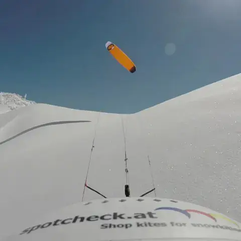 Kite orange dans le ciel, vu depuis la neige