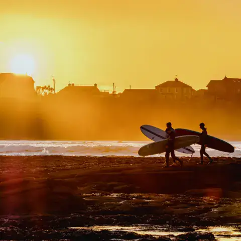 Deux surfeurs avec leurs planches au coucher du soleil