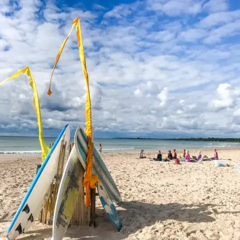 Planches de surf dressées sur la plage, avec des rubans colorés
