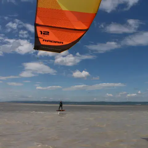 Kite orange au-dessus de la rive peu profonde