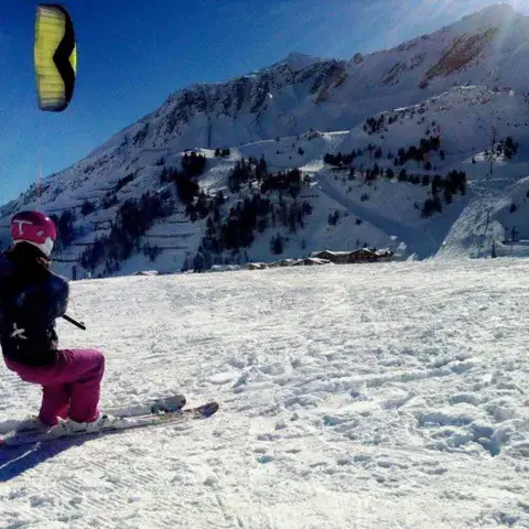 Snowkiter à ski avec un kite jaune en montagne