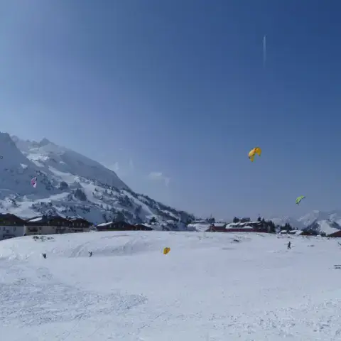 Plusieurs kites de snowkite sur la pente enneigée