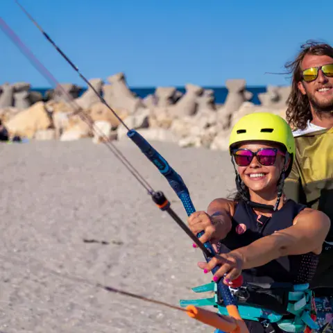 Moniteur et élève tenant la barre d'un kite sur la plage