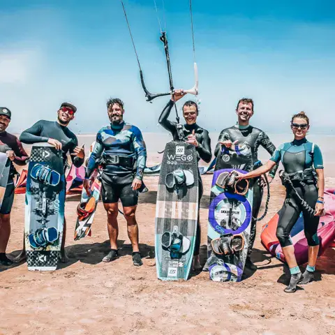 Groupe de riders avec leurs planches de kite sur le sable