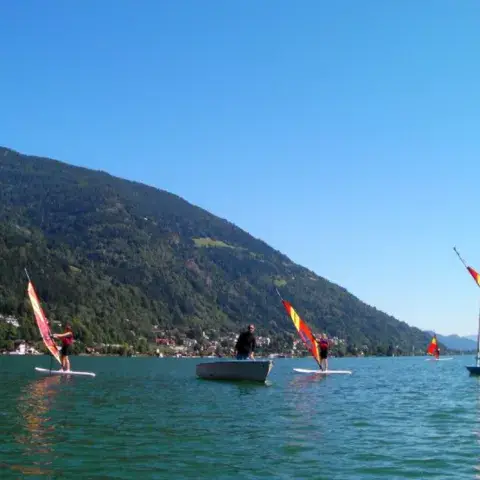 Windsurfeurs et voilier sur le lac, au pied de la montagne