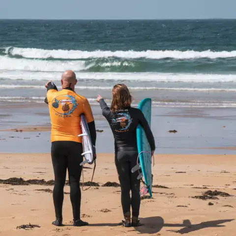 Deux surfeurs sur la plage face aux vagues