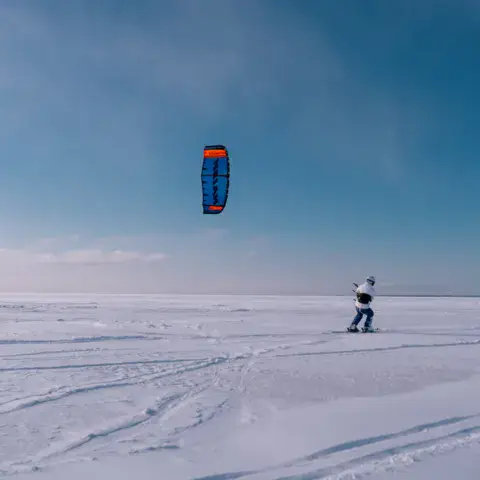 Snowkiteur avec son aile sur une étendue de neige