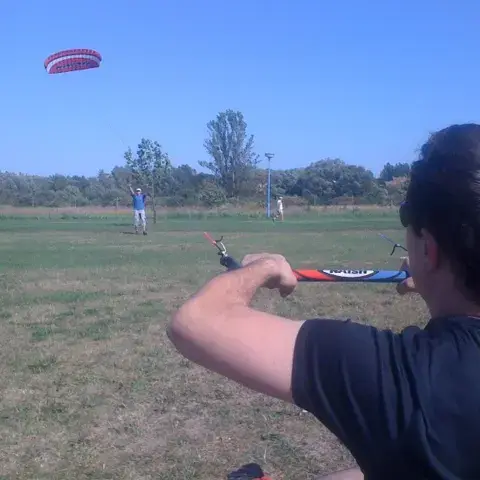 Élève tenant la barre d'un kite d'entraînement dans un champ