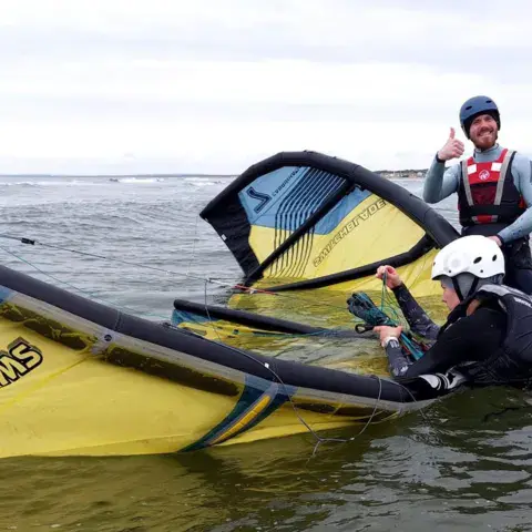 Moniteur et élève qui préparent une aile dans l'eau peu profonde