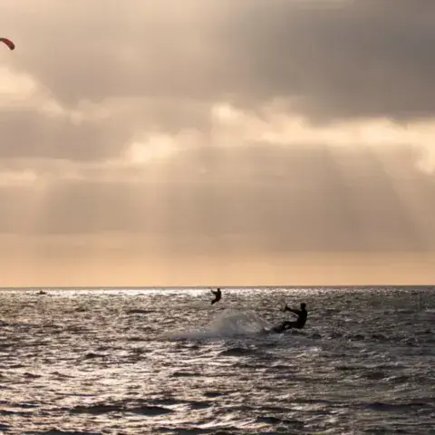 Kitesurfeur sous un ciel de rayons de soleil