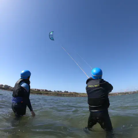 Élèves de kitesurf dans l'eau peu profonde