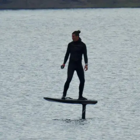 Pratiquant de hydrofoil sur un plan d'eau calme