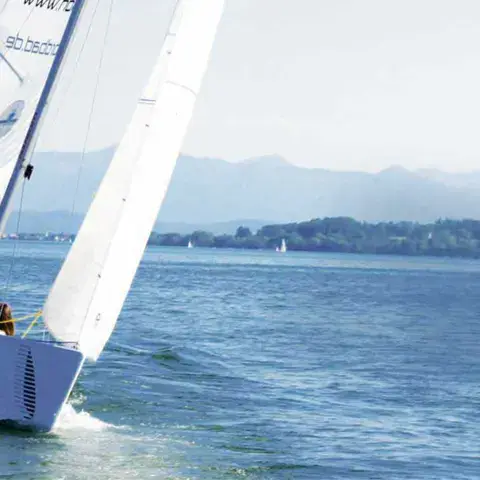 Voilier du centre sous voile, les Alpes au fond
