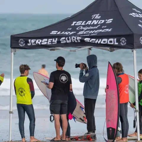 Le stand de l'école sur la plage, avec élèves et planches