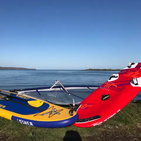 Planches et matériel posés sur la berge, au bord de l'eau