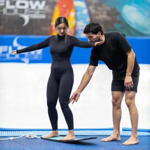 Instructeur corrigeant la position d'une élève sur la planche