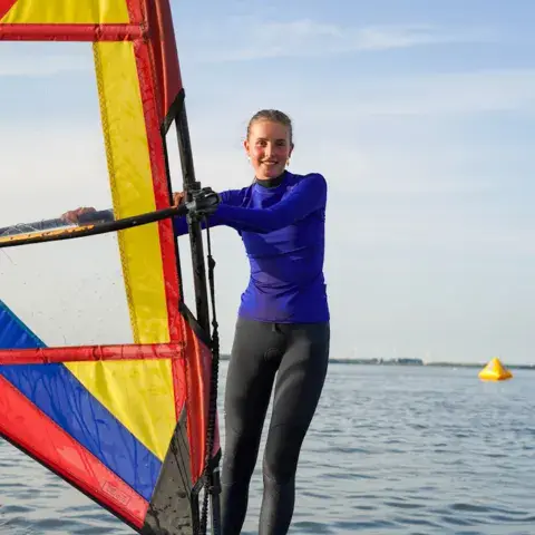 Débutante debout sur une planche de windsurf