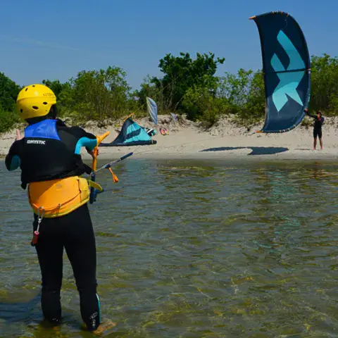 Un élève équipé d'un casque et d'un gilet pendant un cours de kitesurf