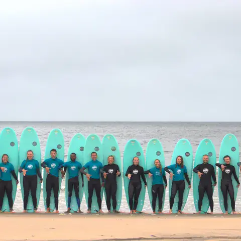 Groupe en combinaison avec les planches de l'école sur la plage