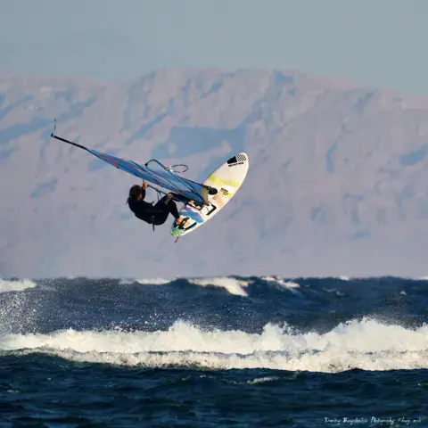 Un windsurfeur saute une vague devant les montagnes du Sinaï