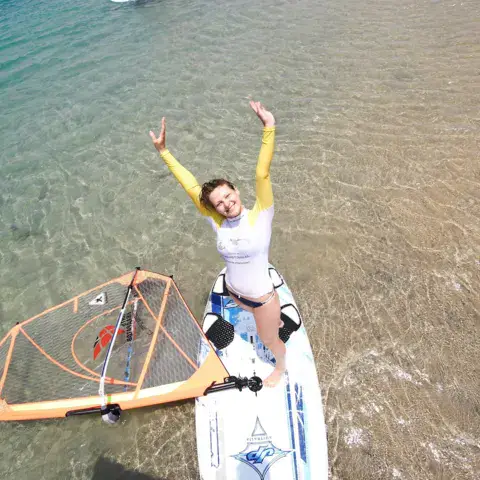 Une élève sur sa planche de windsurf en eau peu profonde