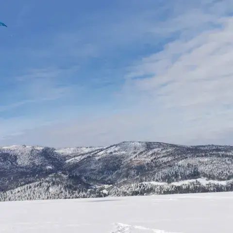 Snowkite sur un plateau enneigé face aux montagnes