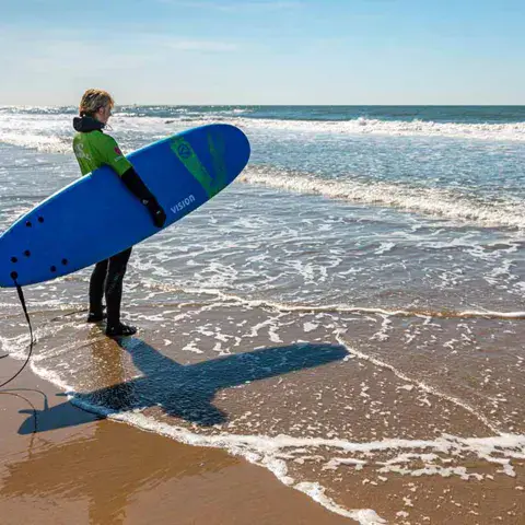 Élève de surf avec sa planche sur le rivage