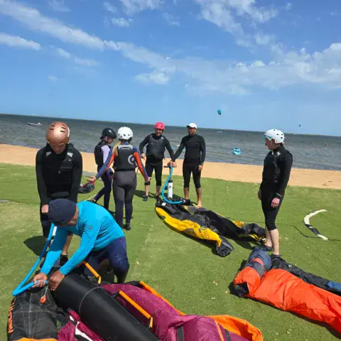 Groupe en combinaison autour du matériel sur la plage