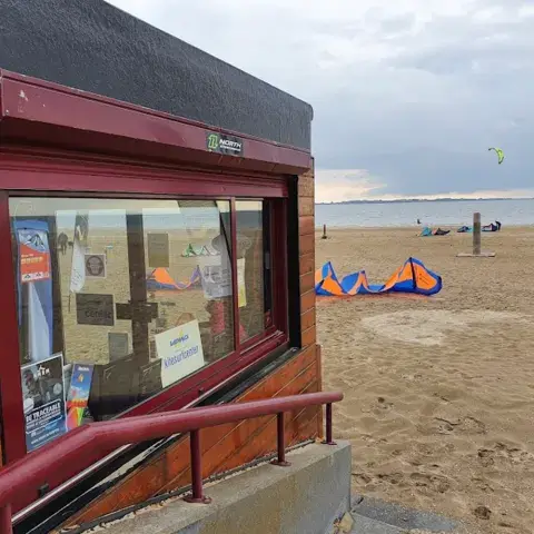 Cabane de l'école face à la plage et à des kites posés au sol