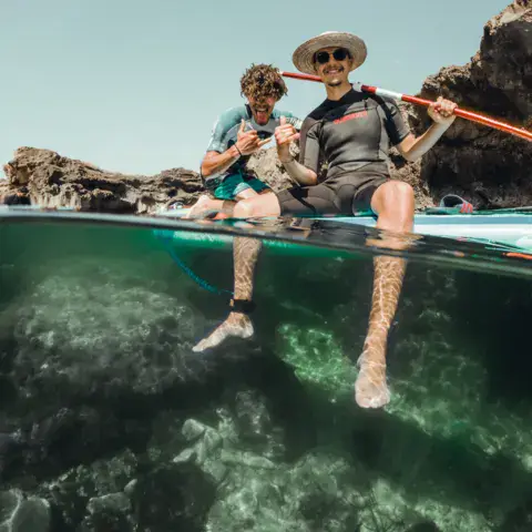 Deux personnes en stand-up paddle au-dessus d'un fond rocheux