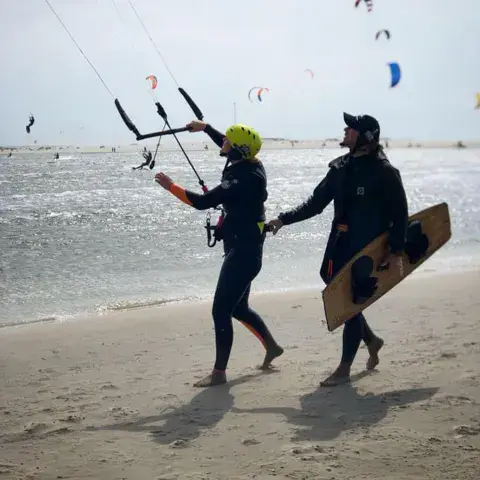 Moniteur et élève avec la barre et la planche sur la plage