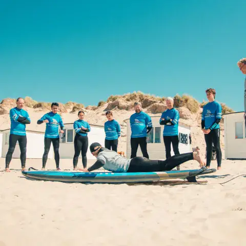 Un groupe d'élèves s'exerce au take-off sur la plage